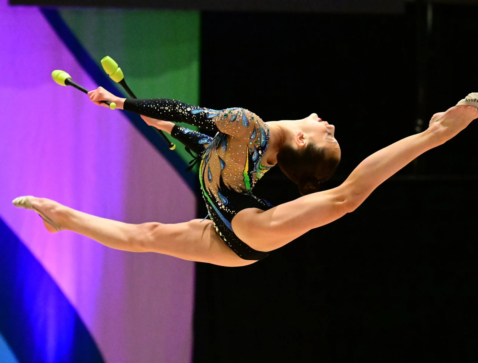 Gymnast performing a split leap with clubs